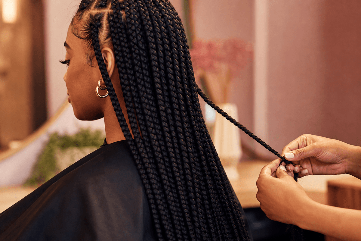 Long box braids being finished in a salon